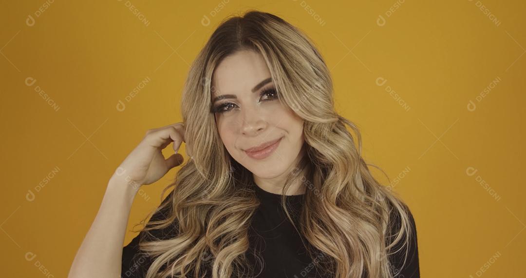Jovem linda loira caucasiana feliz. Conceito de sucesso e realização. Alegre mulher loira bonita sobre fundo amarelo.