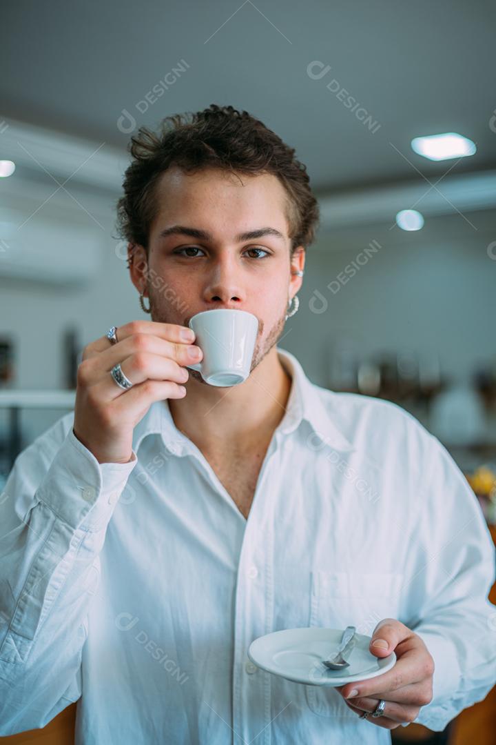 Jovem latino feliz desfrutando de café em um café de rua