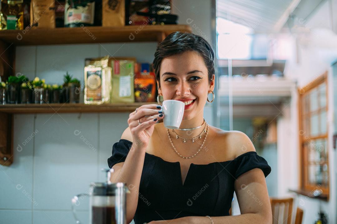 Jovem linda e feliz mulher latina desfrutando de café em um café de rua