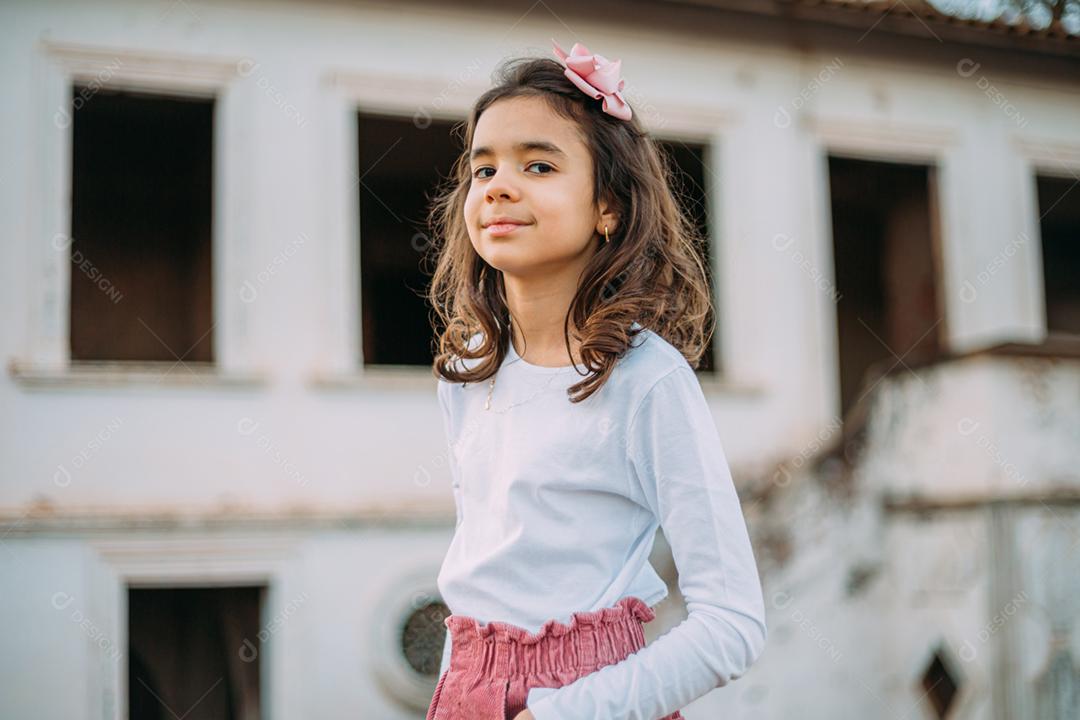 Menina criança bonita feliz sobre o fundo verde desfocado. Garoto na fazenda. Povo latino.