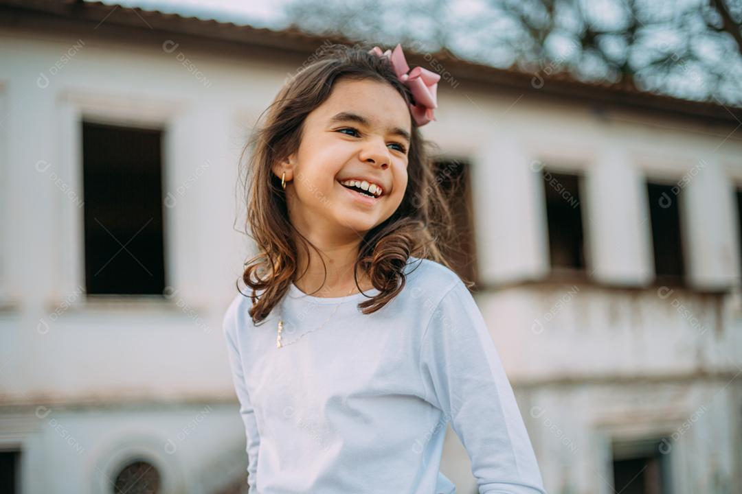 Menina criança bonita feliz sobre o fundo verde desfocado. Garoto na fazenda. Povo latino.