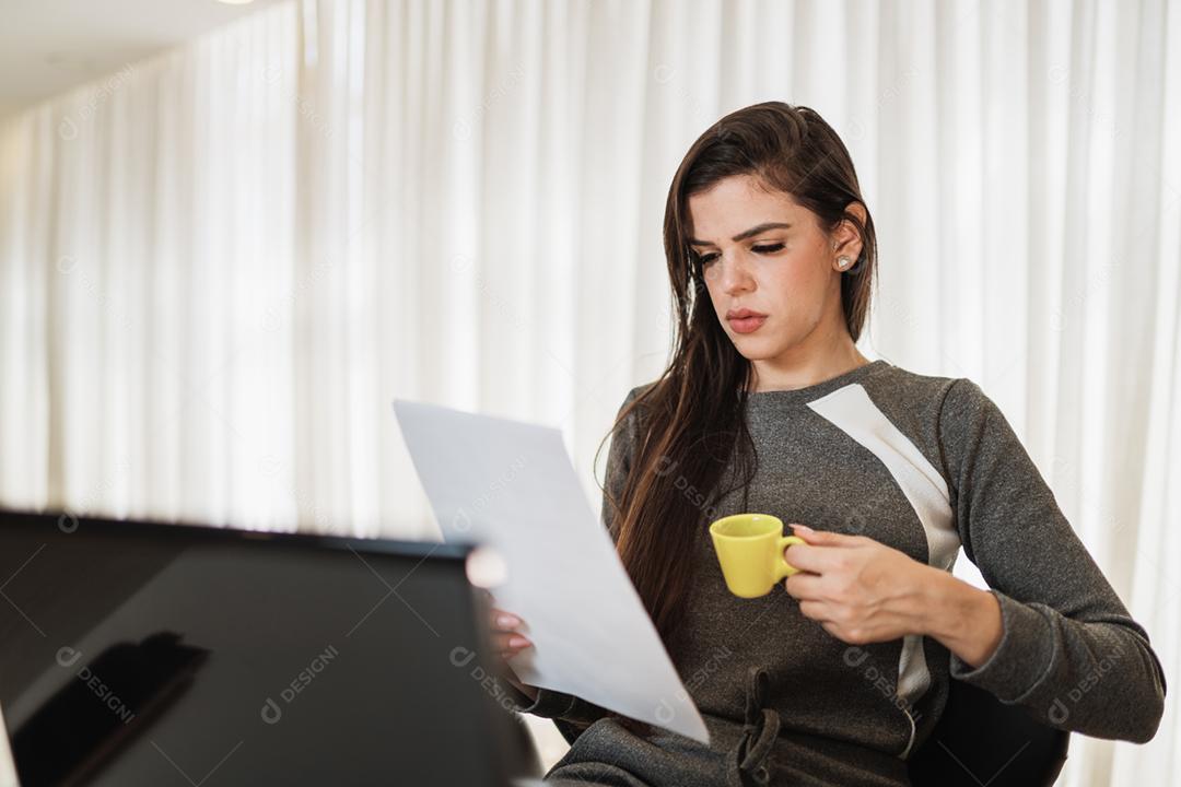 Jovem linda brasileira trabalhando com laptop enquanto está sentado na mesa de escritório, trabalhando em casa conceito.