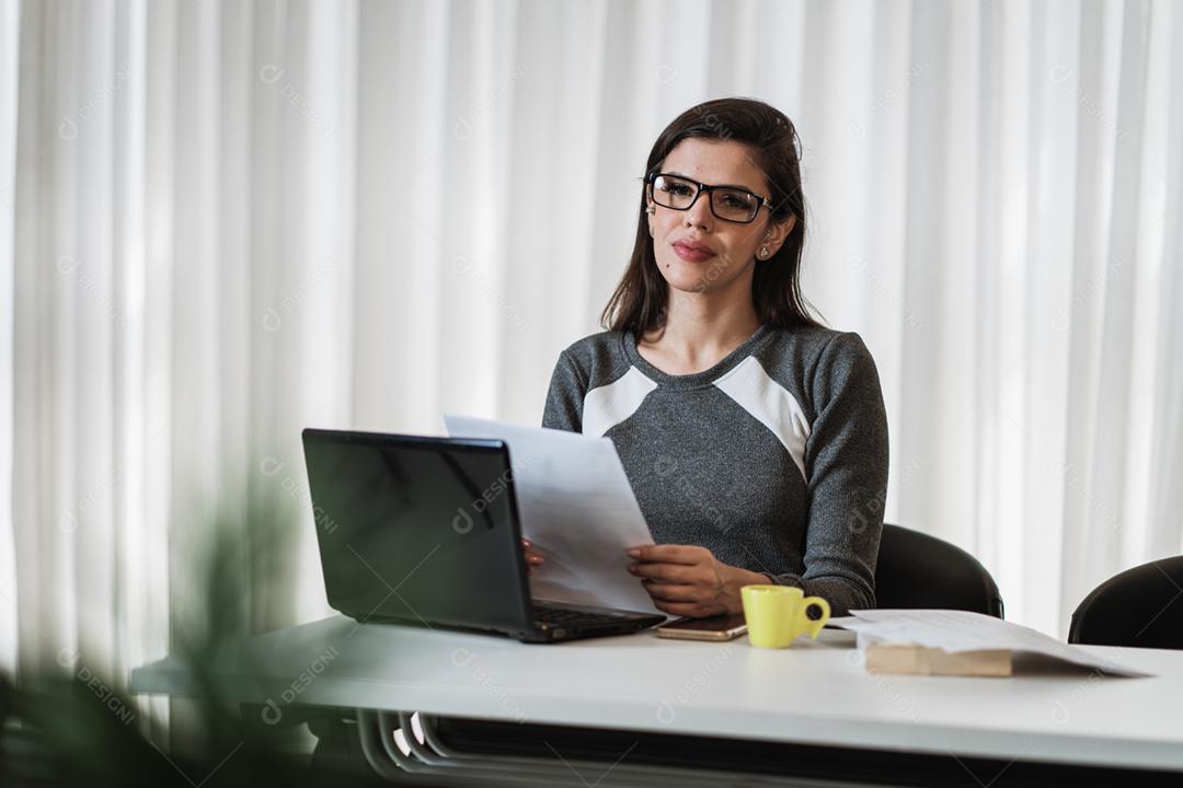 Mulher latina estressada que sofre de enxaqueca com um laptop sentado em uma mesa em casa