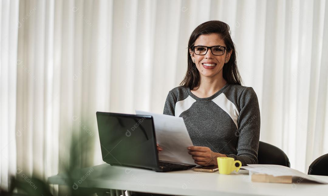 Jovem linda brasileira trabalhando com laptop enquanto está sentado na mesa de escritório, trabalhando em casa conceito.