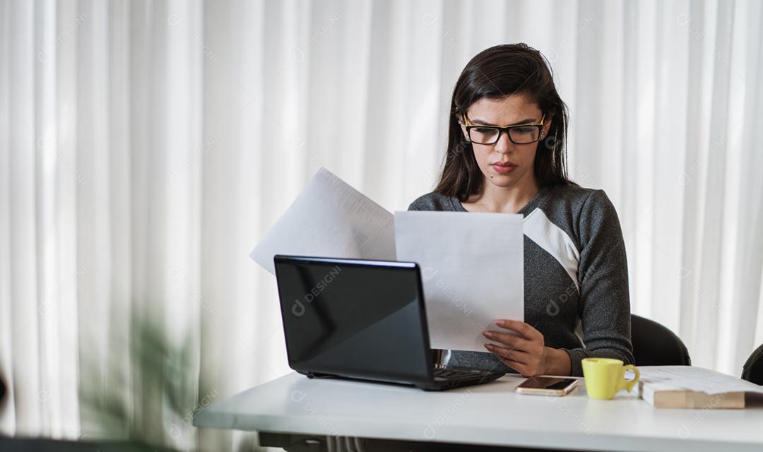 Mulher latina estressada que sofre de enxaqueca com um laptop sentado em uma mesa em casa