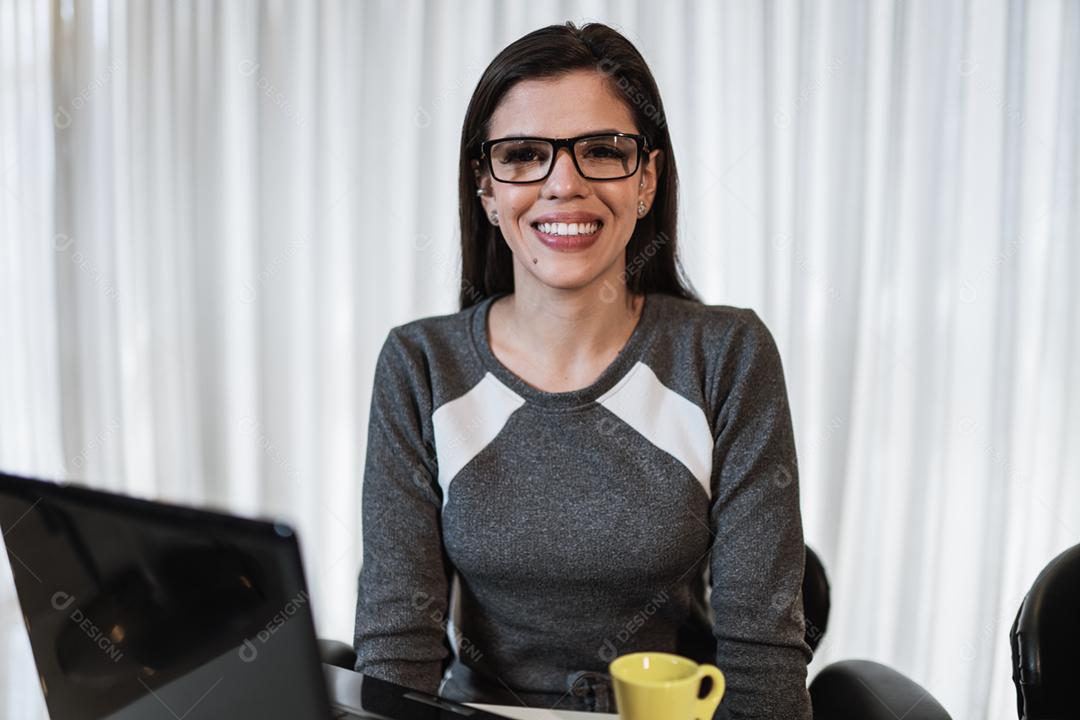 Jovem linda brasileira trabalhando com laptop enquanto está sentado na mesa de escritório