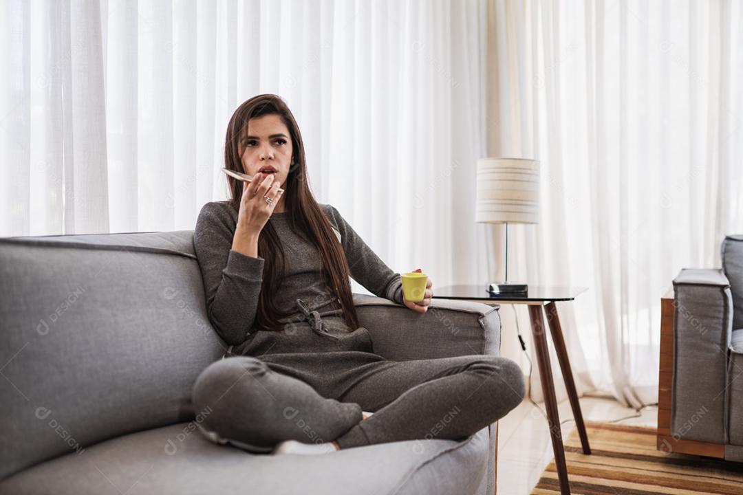 Feliz dama latina relaxa em casa sozinha, sente-se na sala e compartilhe boas notícias nas mídias sociais via celular.