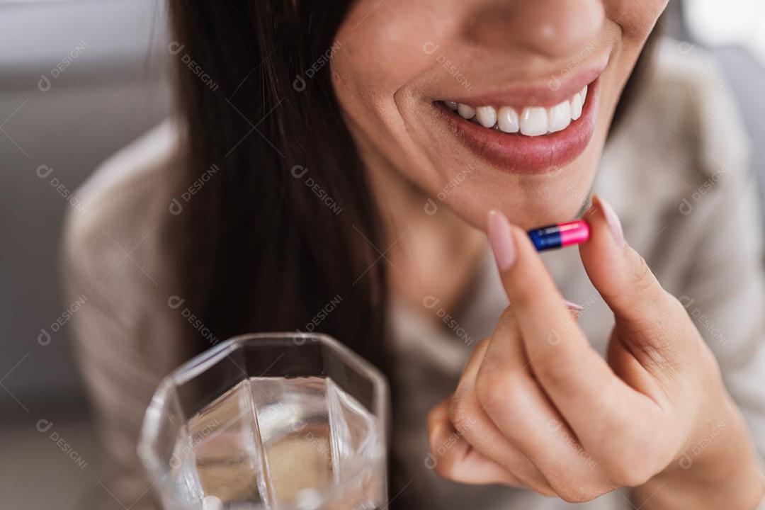 Feche de mulher segurando vários comprimidos, pílulas e copo de água. Tomar vitaminas, medicamentos