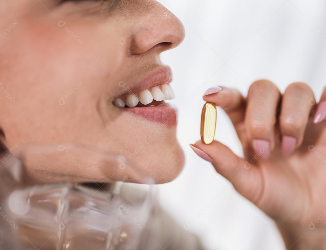 Mulher latina segurando uma cápsula de óleo de peixe Omega 3 em casa.