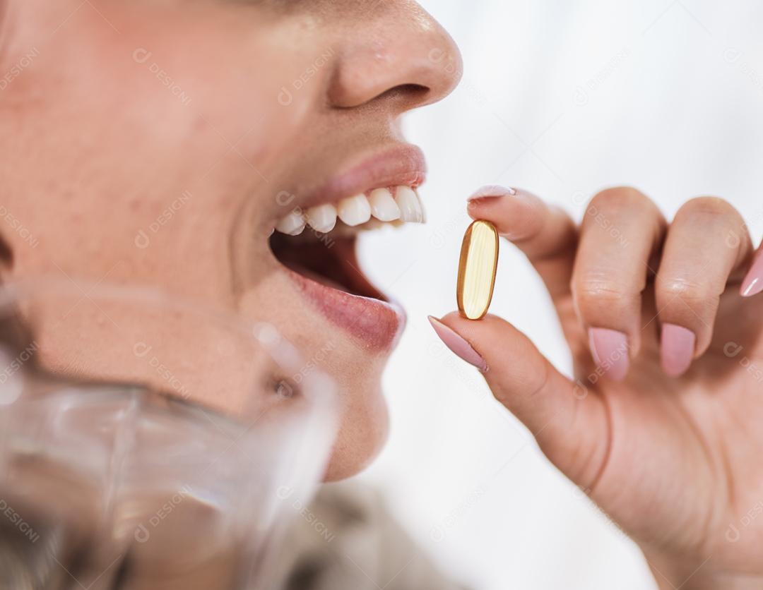 Mulher latina segurando uma cápsula de óleo de peixe Omega 3 em casa.