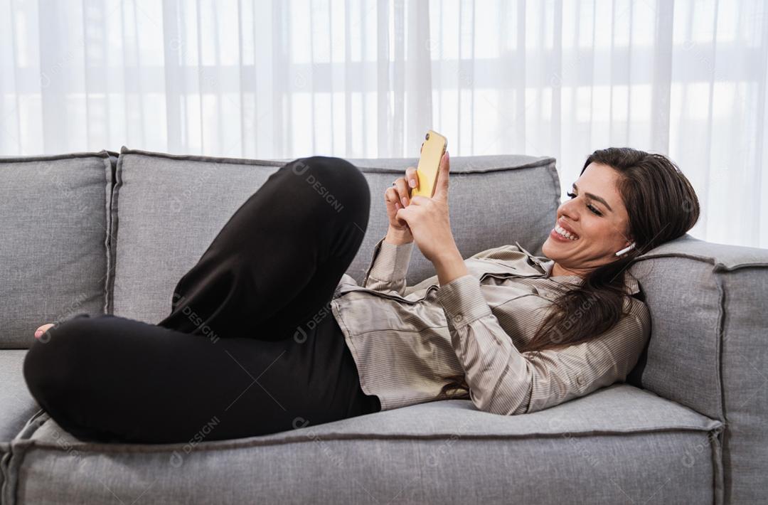 O cliente sorridente da senhora latina segura o cartão de crédito do telefone móvel para fazer compras on-line