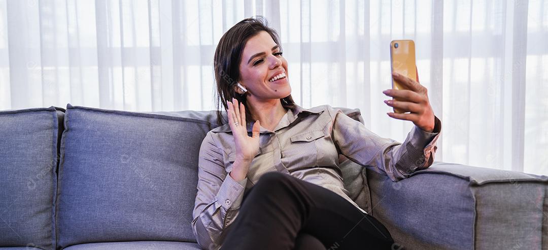 Feliz dama latina relaxa em casa sozinha, sente-se na sala e compartilhe boas notícias nas mídias sociais