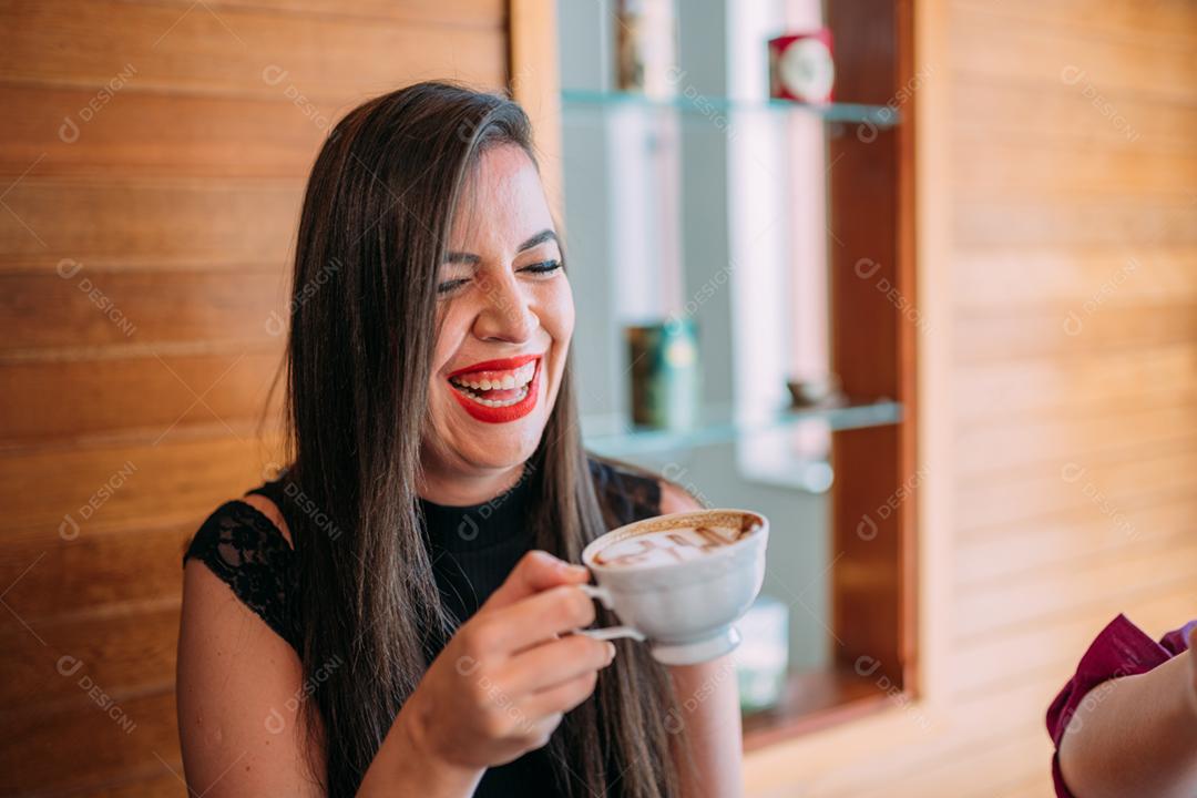 Jovem e linda mulher latina feliz desfrutando de cappuccino em um café de rua