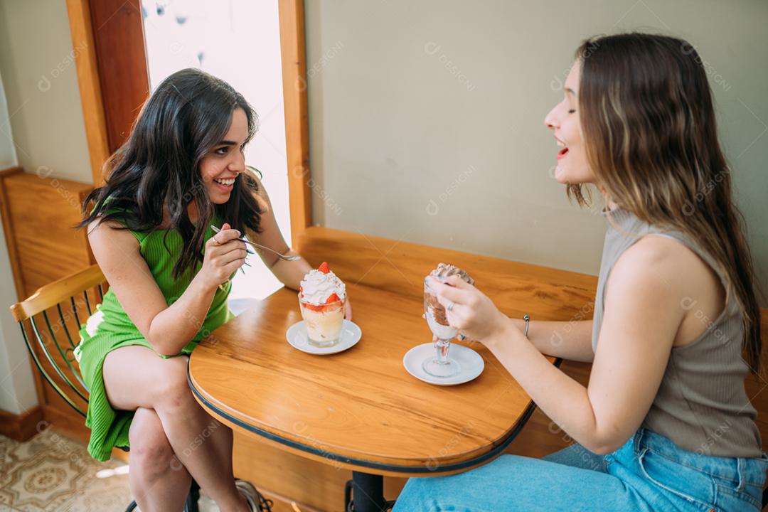 Jovens garotas latinas sentadas no café ouvindo a história de vida engraçada de seu amigo