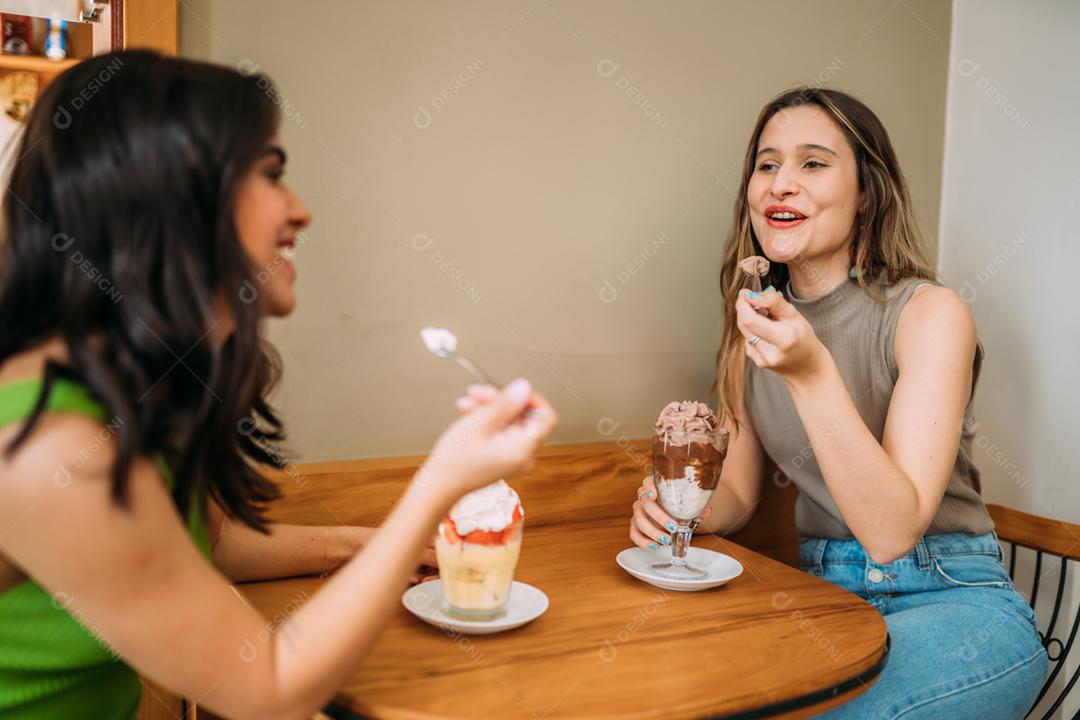 Jovens garotas latinas sentadas no café ouvindo a história de vida engraçada de seu amigo
