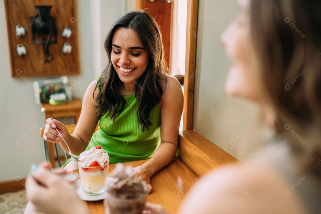 Jovens garotas latinas sentadas no café ouvindo a história de vida engraçada de seu amigo