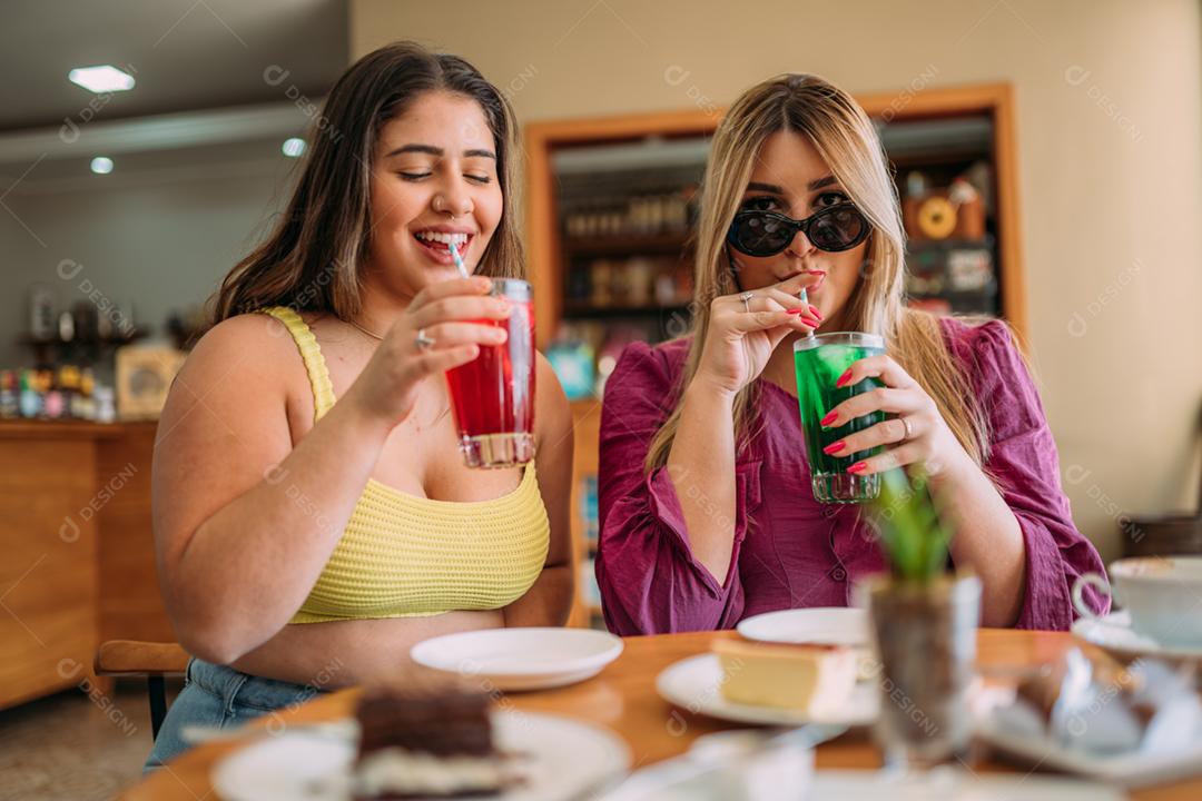 Animadas lindas duas mulheres latinas assistem a um vídeo engraçado no celular moderno, têm expressões