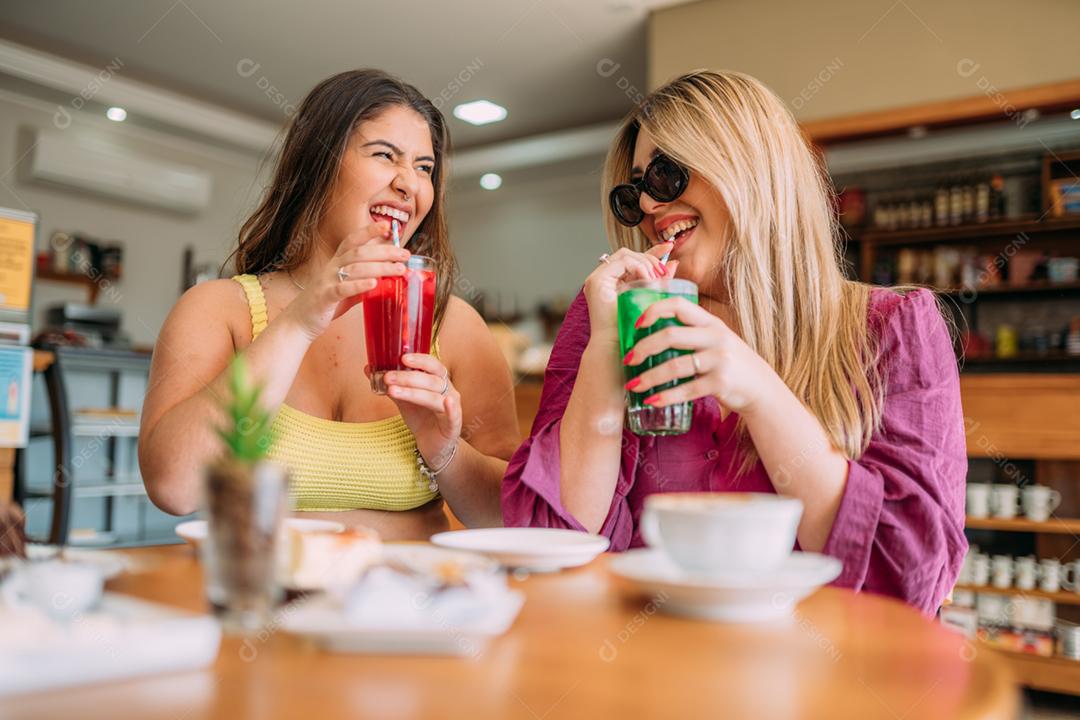 Animadas lindas duas mulheres latinas assistem a um vídeo engraçado no celular moderno, têm expressões