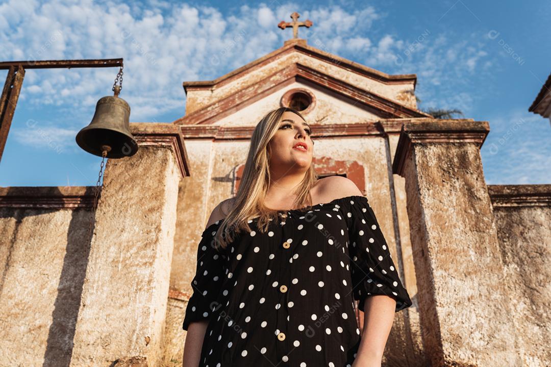 Retrato de uma jovem latina elegante e elegante em frente a uma pequena capela