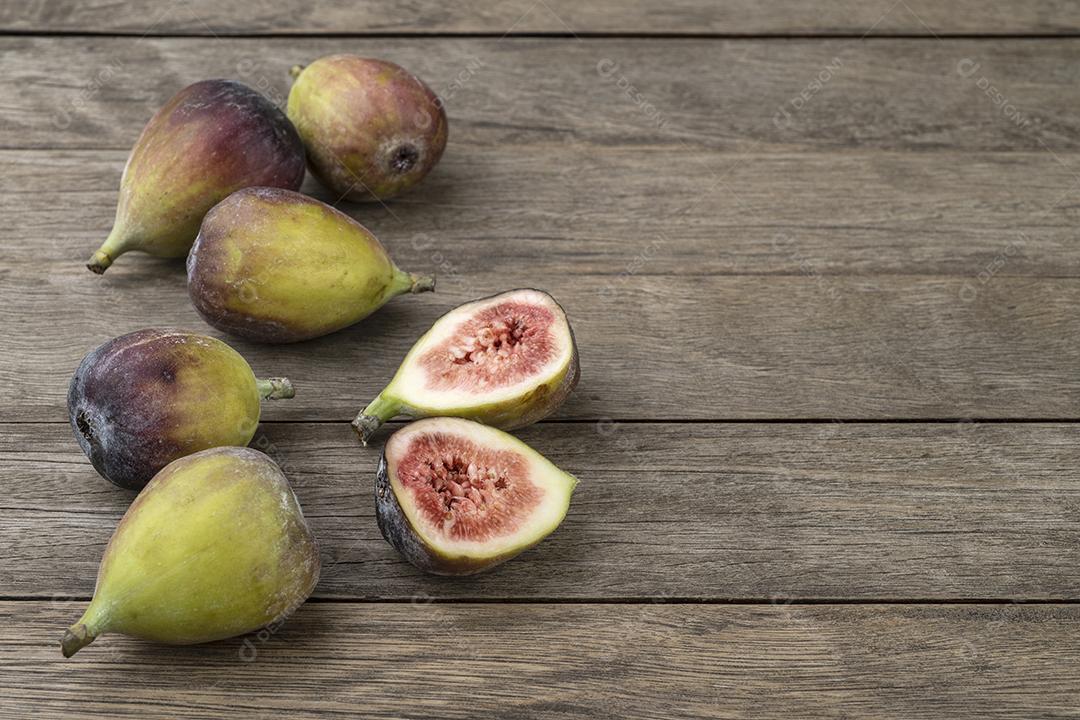 Figos com frutas cortadas sobre mesa de madeira