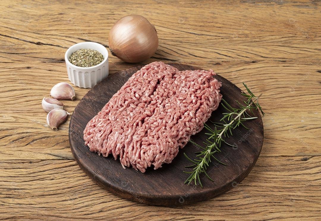Carne moída sobre tábua de madeira com temperos
