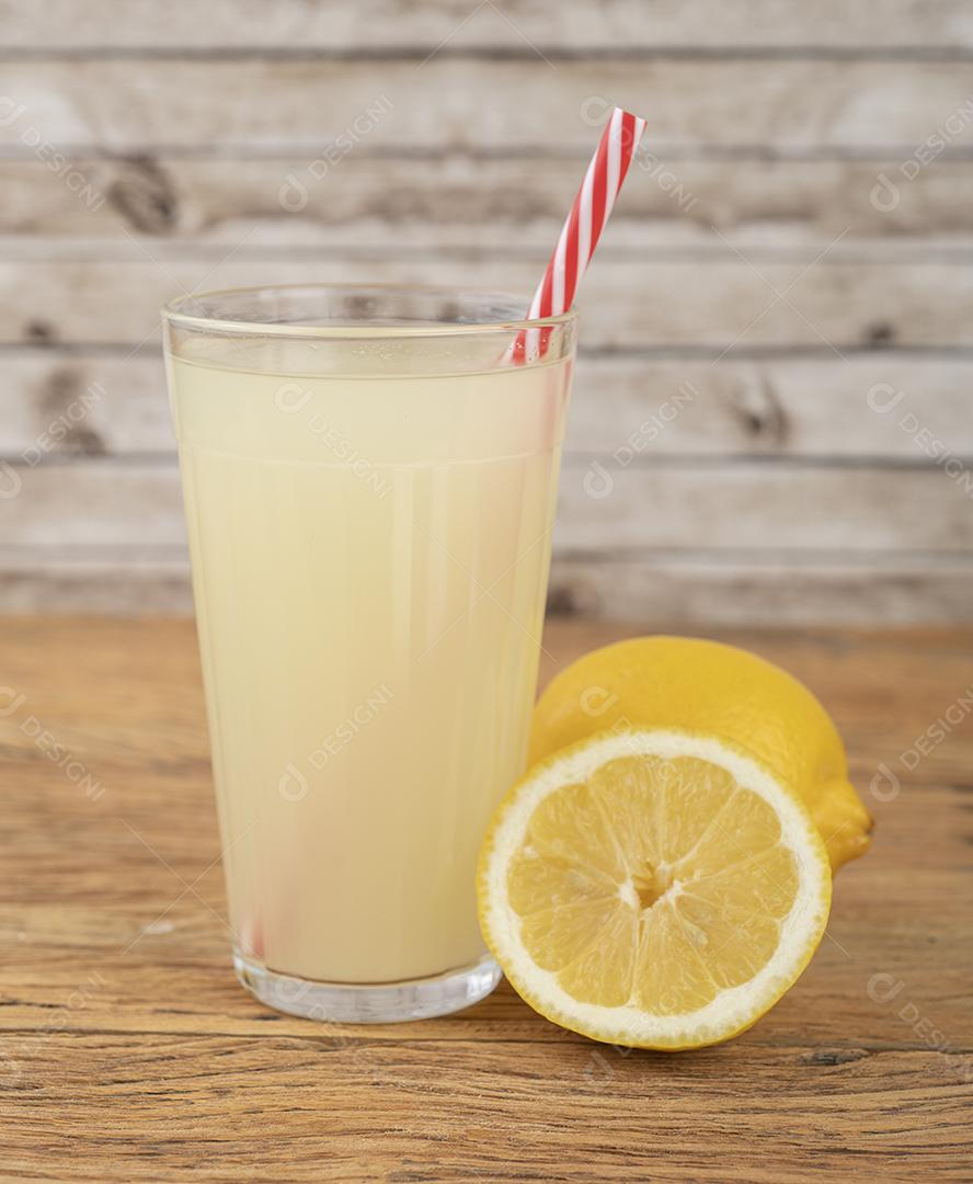 Suco de limão siciliano em um copo com frutas sobre mesa de madeira.
