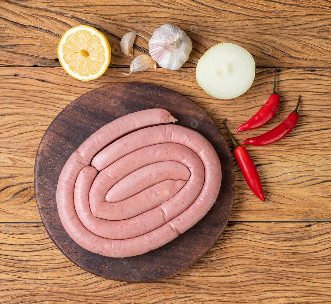 Linguiça de porco crua em um javali de madeira com limão siliciano