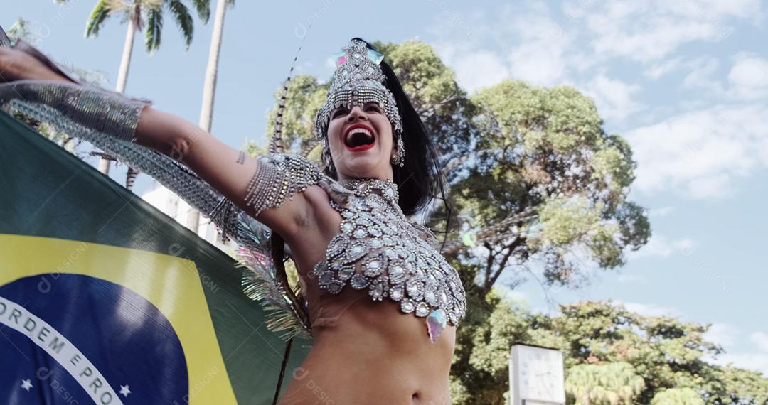 Linda mulher brasileira vestindo fantasia de carnaval colorida e bandeira do Brasil durante o desfile de rua de carnaval na cidade.
