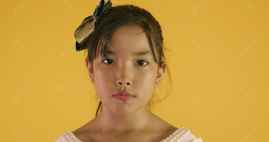 Linda garota asiática triste em fundo amarelo. Feliz menina asiática triste.