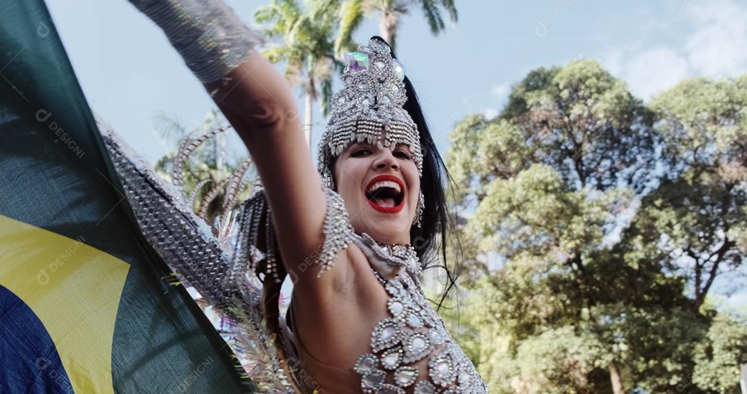 Linda mulher brasileira vestindo fantasia de carnaval colorida e bandeira do Brasil durante o desfile de rua de carnaval na cidade.