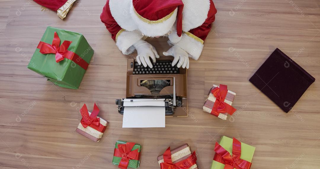 Vista superior do Papai Noel escrevendo em uma velha máquina de escrever. Conceito de letras, anotando