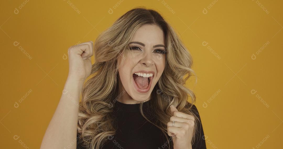 Jovem linda loira caucasiana feliz. Conceito de sucesso e realização. Alegre mulher loira bonita sobre fundo amarelo.