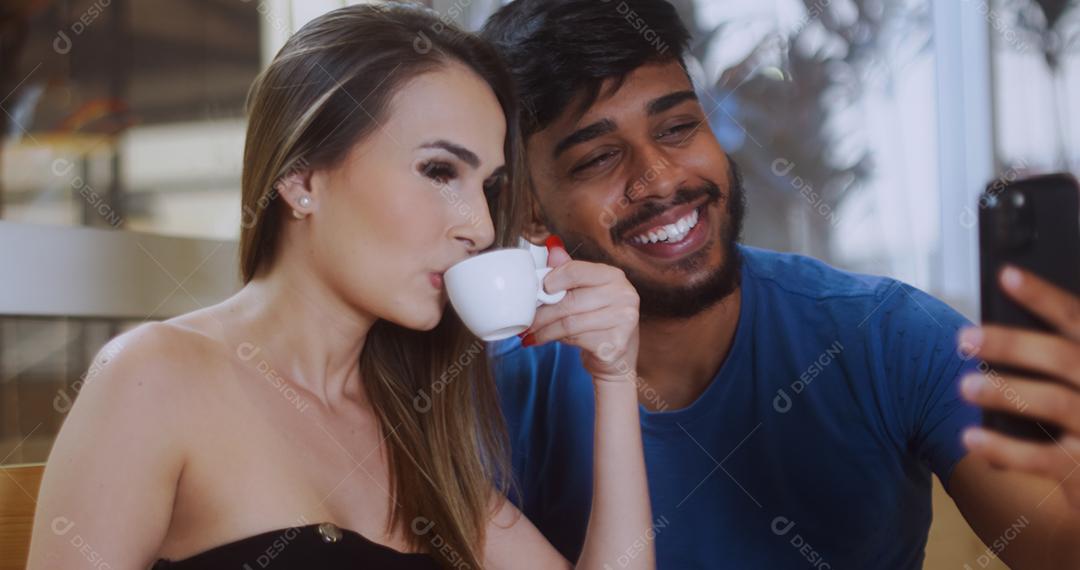 Jovem casal latino em uma videoconferência com seu celular.