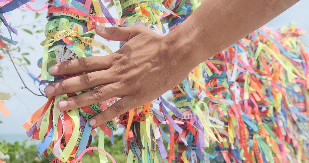 Closeup de fitas coloridas na Bahia, Brasil. Mão de homem fazendo um pedido com fitas brasileiras. Fé.
