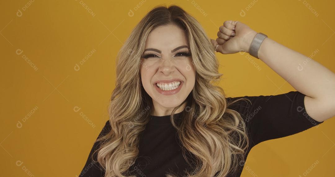 Jovem linda loira caucasiana feliz. Conceito de sucesso e realização. Alegre mulher loira bonita sobre fundo amarelo.