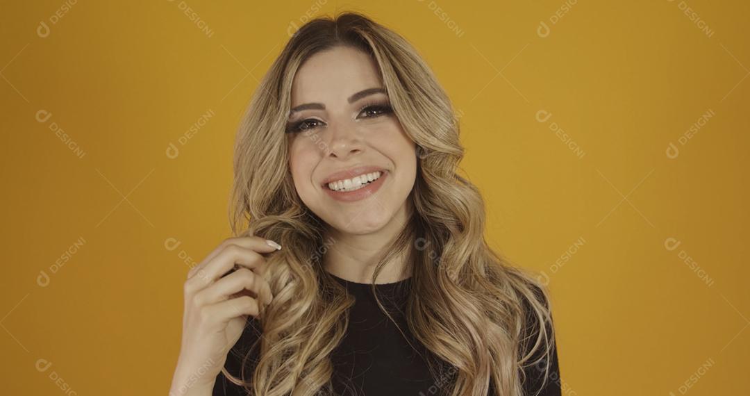 Jovem linda loira caucasiana feliz. Conceito de sucesso e realização. Alegre mulher loira bonita sobre fundo amarelo.