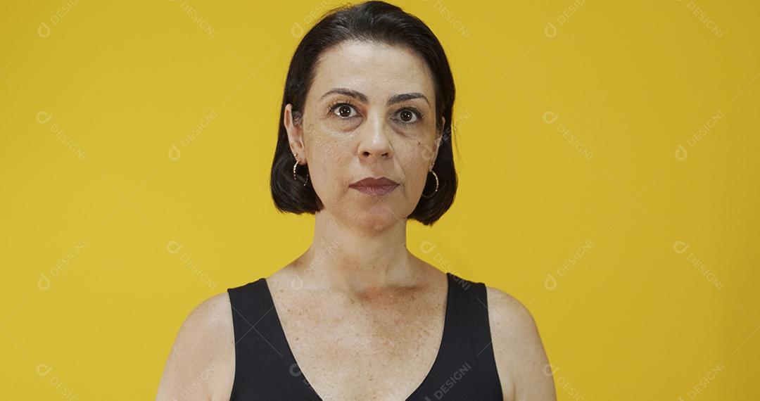 Mulher atraente de meia-idade com belo sorriso na parede amarela