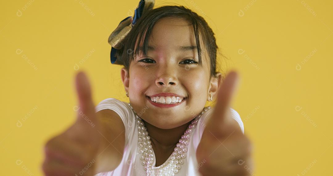 Linda garota asiática sentada em fundo amarelo. Feliz