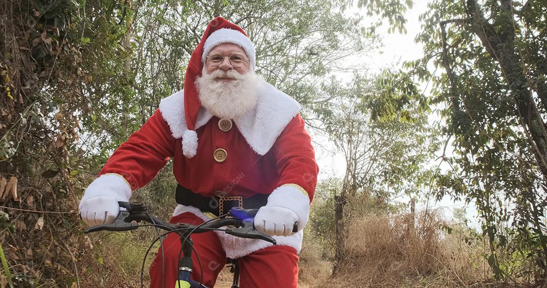 Papai Noel andando de bicicleta na estrada de terra.