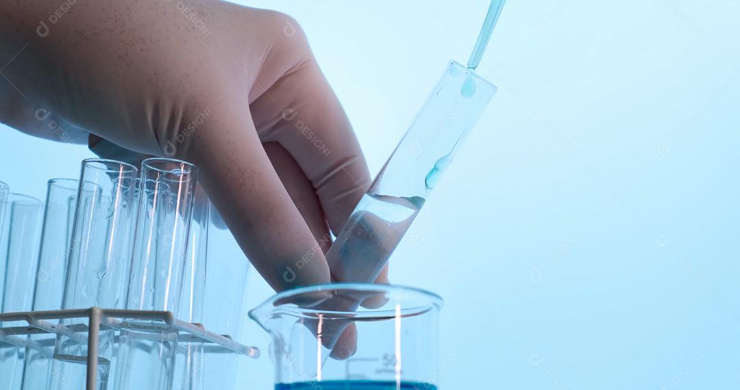 Mão de cientista segurando frasco com vidros de laboratório e tubo de ensaio