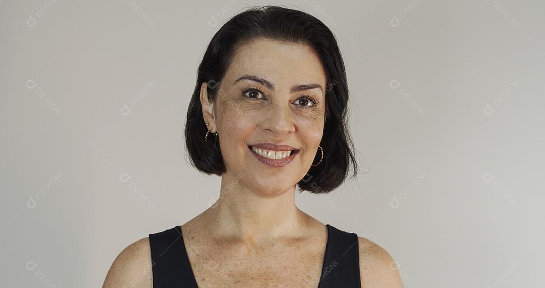 Mulher atraente de meia-idade com belo sorriso na parede cinza