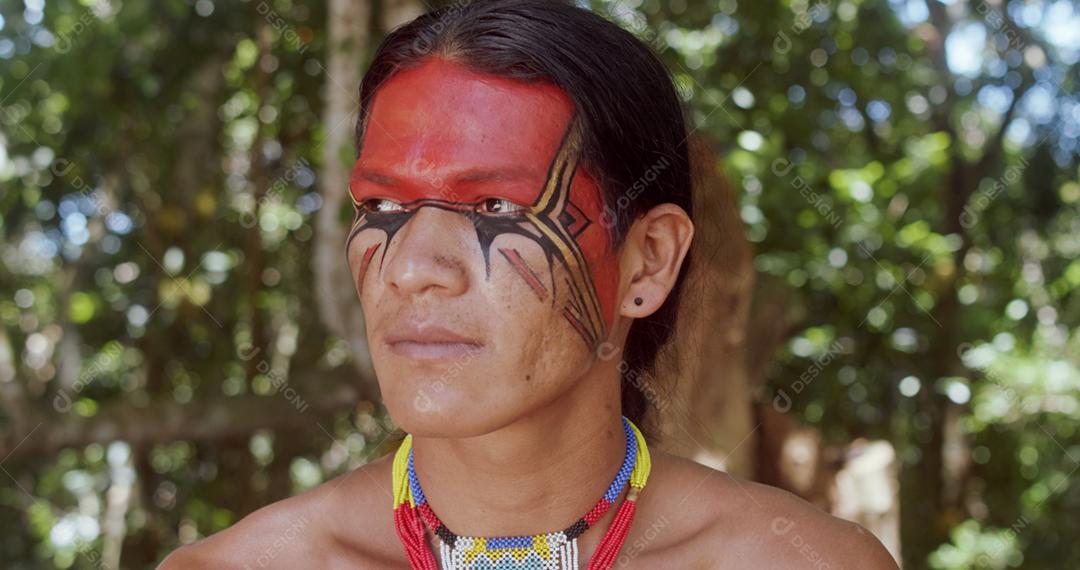 Índio da tribo Pataxó sorrindo. Índio brasileiro do sul da Bahia com colar e pinturas faciais tradicionais olhando para a esquerda