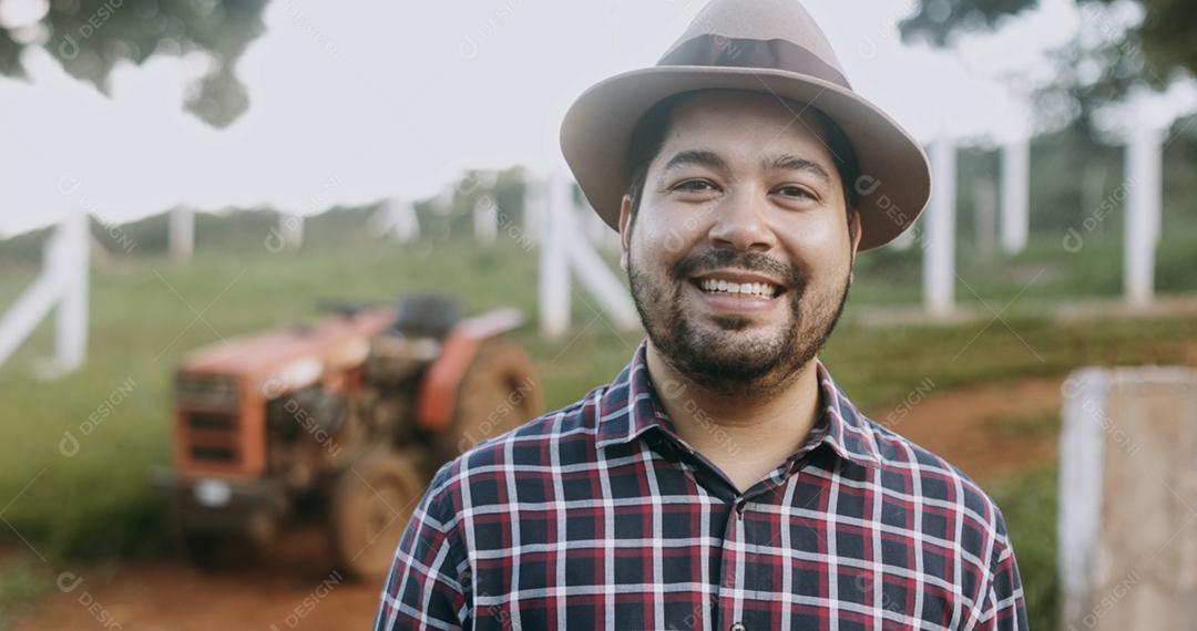 Retrato de jovem agricultor latino na camisa casual na fazenda no fundo da fazenda.