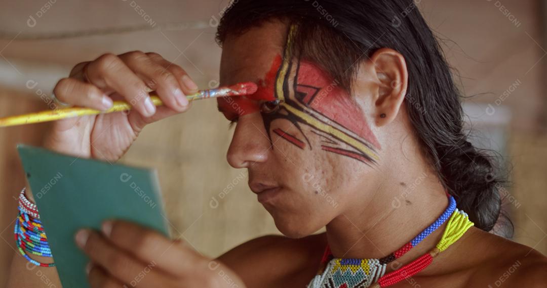 Índio da tribo Pataxó, usando espelho e pintando o rosto.