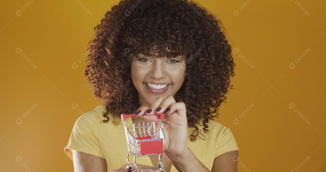 Menina com pequeno cartão de compras. Sorrindo e dançando mulher de cabelo encaracolado no conceito de compras