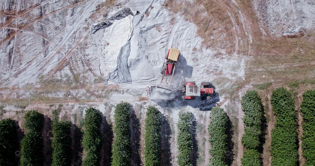 Trator aplicando calcário ao solo para corrigir a acidez