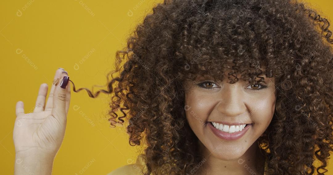 Feliz rindo mulher africana americana com seu cabelo encaracolado em fundo amarelo. Rindo mulher encaracolada