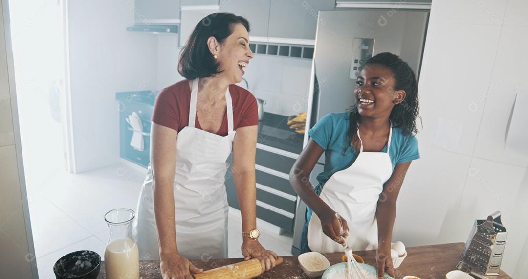 Família jovem cozinhar comida na cozinha. Menina feliz com a mãe misturando a massa. Mãe e filho preparando a massa