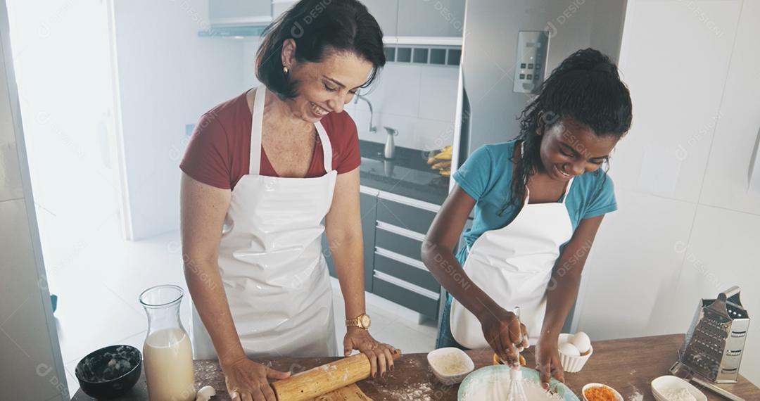 Família jovem cozinhar comida na cozinha. Menina feliz com a mãe misturando a massa. Mãe e filho preparando a massa