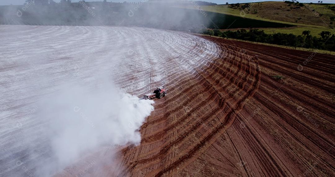 Trator aplicando calcário ao solo para corrigir a acidez